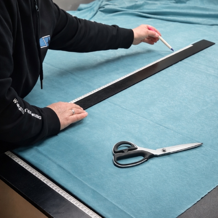Die Inhaberin Genia Meinhardt zeichnet auf einem Zuschneidetisch einen blauen Stoff zum schneiden an.